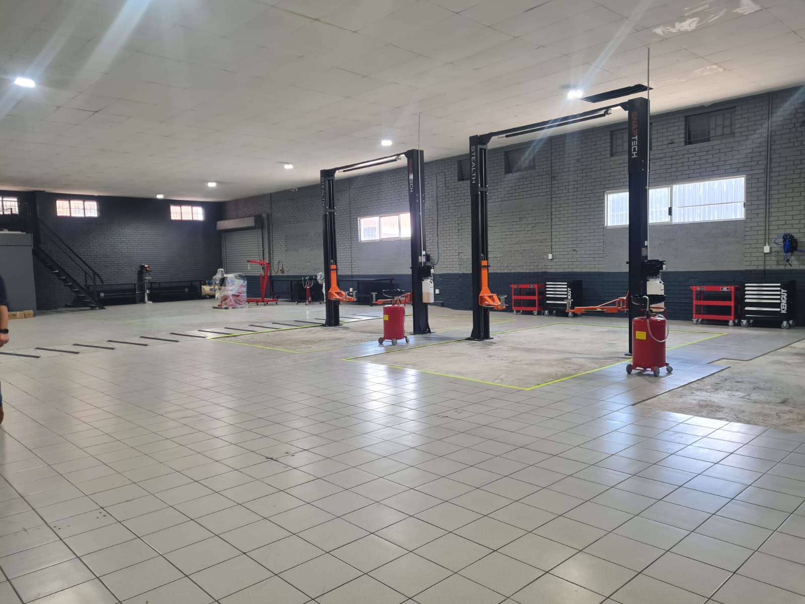 Industrial garage interior with car lifts, tool chests, and tiled flooring